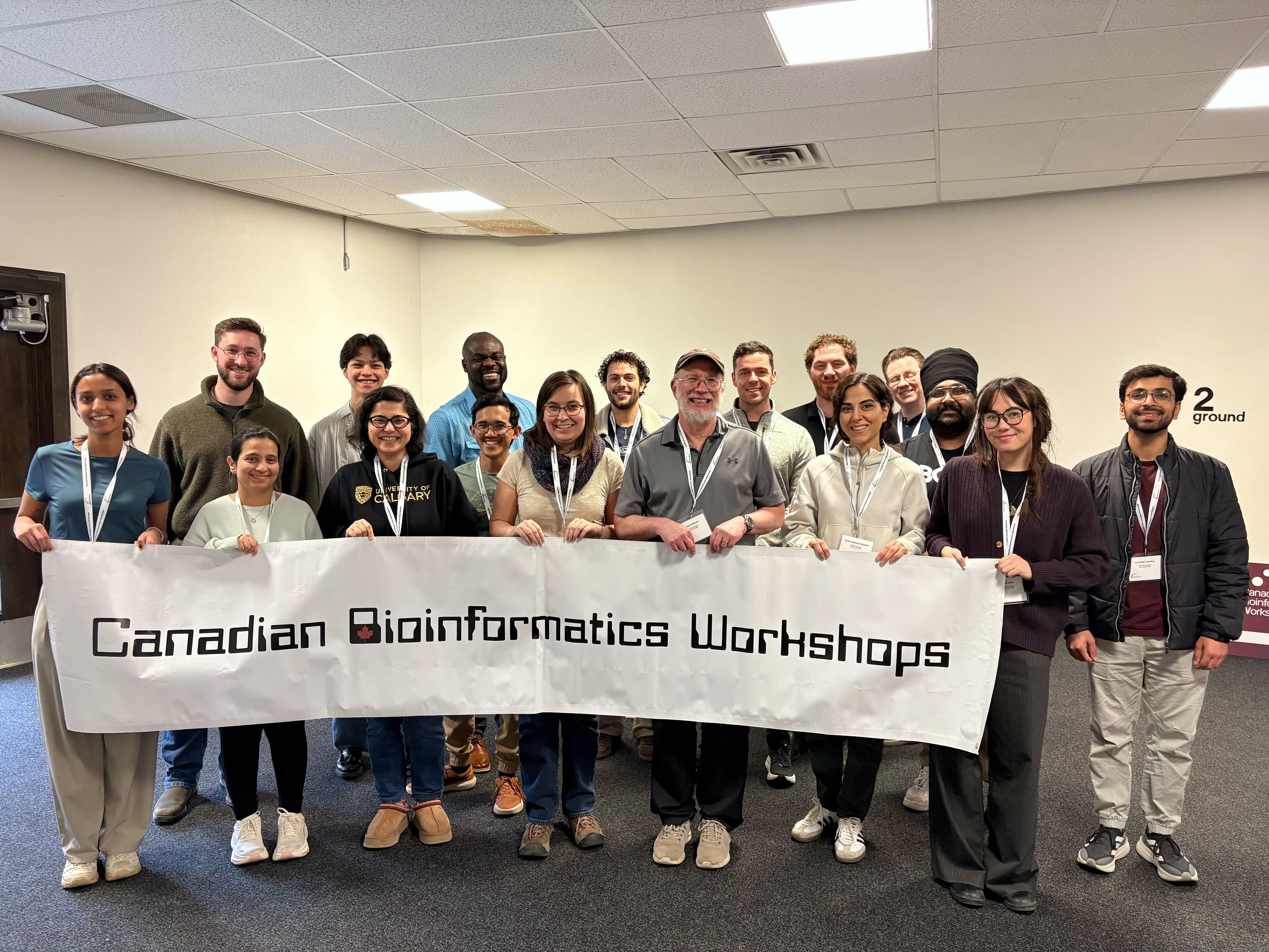 Group photo of Edmonton participants standing behind a white banner with black text reading 'Canadian Bioinformatics Workshops'.